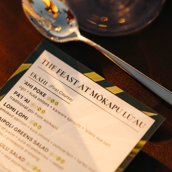 Lūʻau menu next to a spoon on a table.