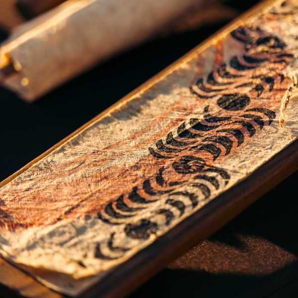 Close-up of a patterned, aged scroll with repetitive black motifs.
