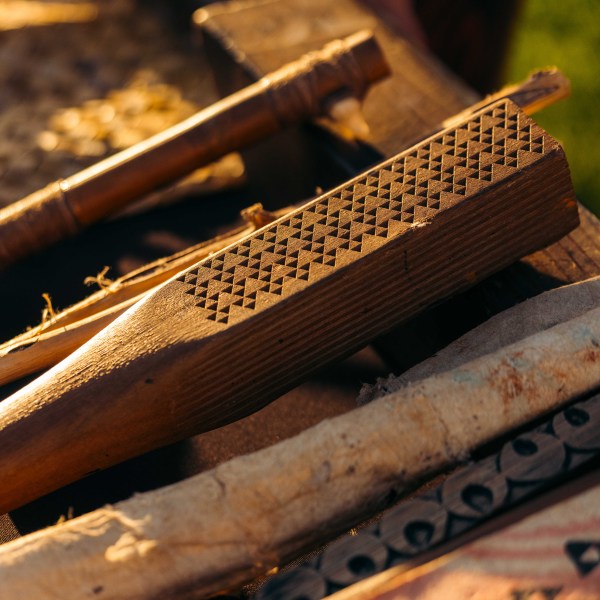 Close-up of a wooden tool with a textured grip, surrounded by other wooden items.