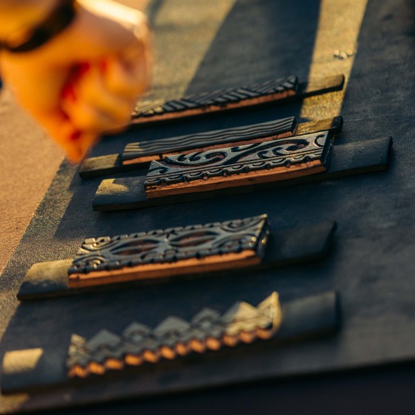 Person arranging decorative knives on a table under sunlight.