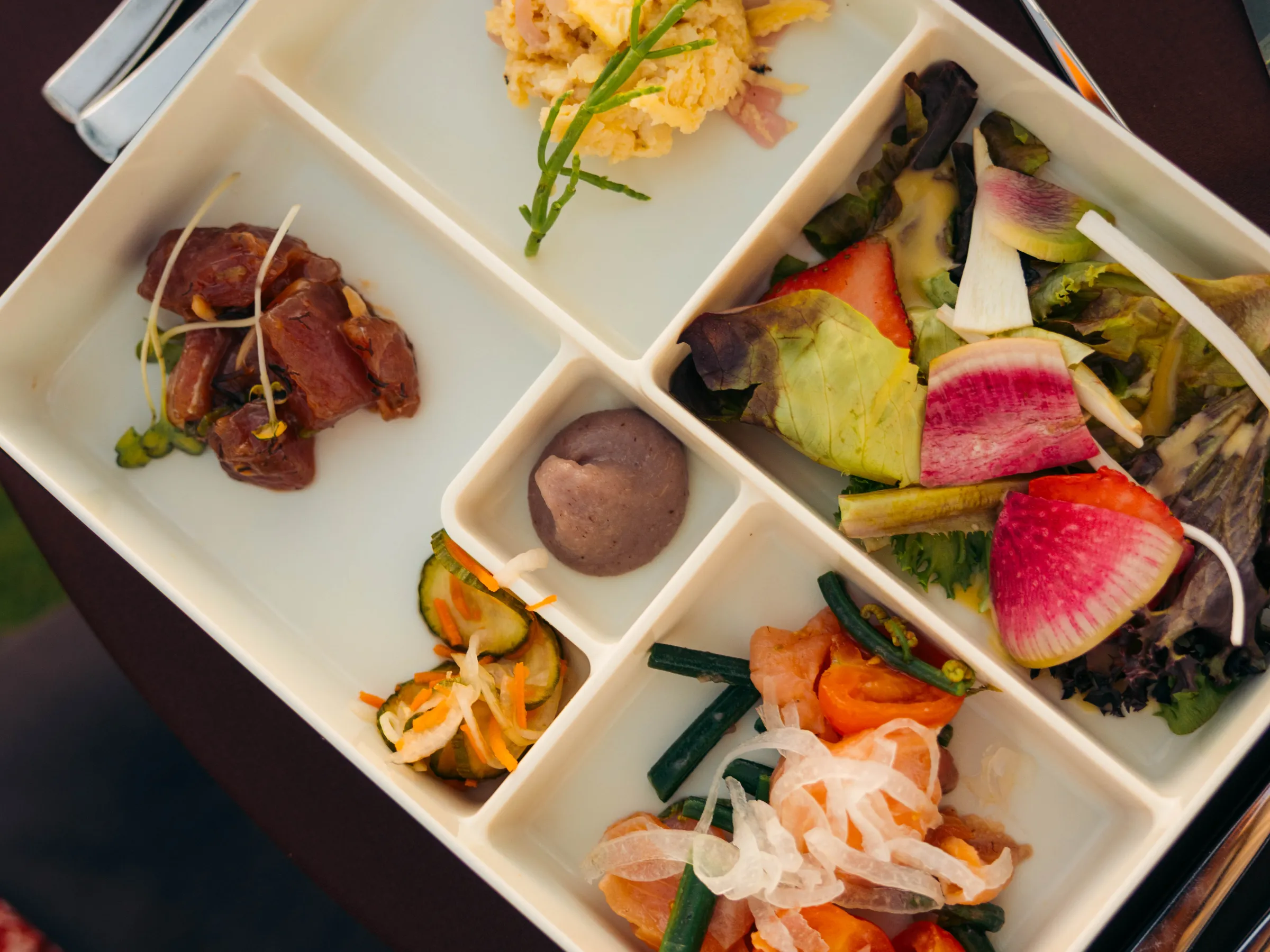Bento box with assorted dishes, including salad and vegetables.